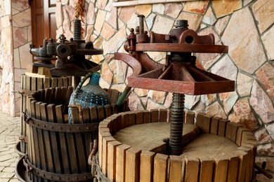 Photo of Metal winepresses in wooden barrels near stone wall