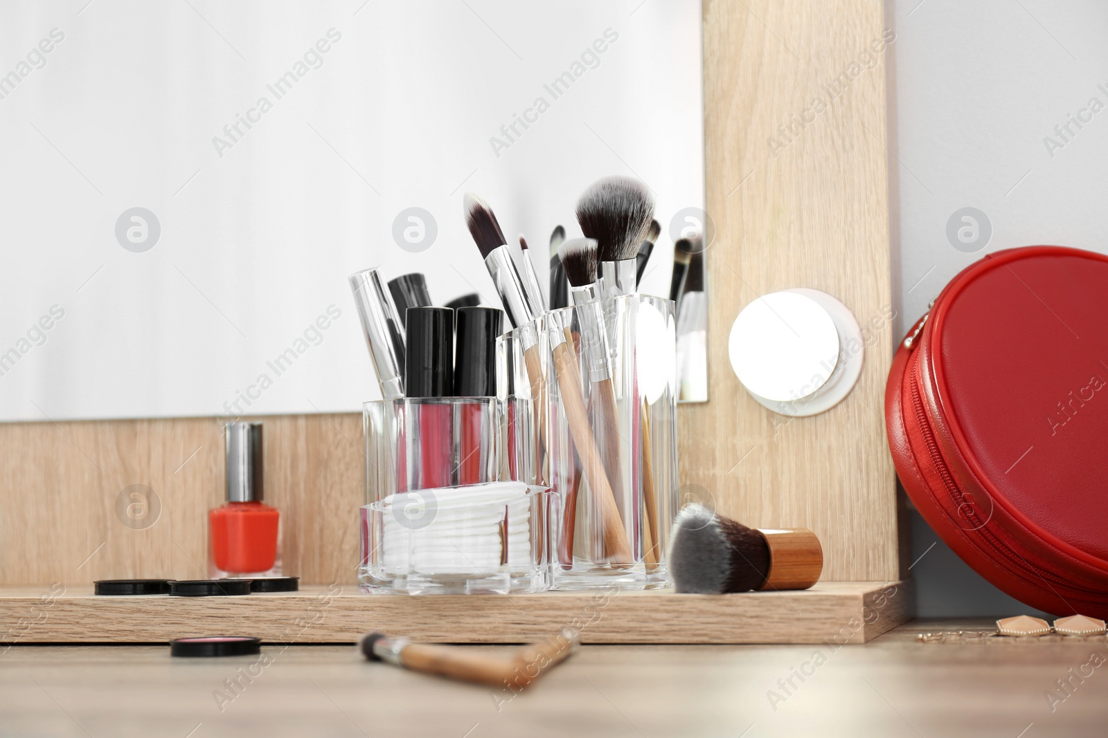 Photo of Organizer with cosmetic products for makeup on table near mirror