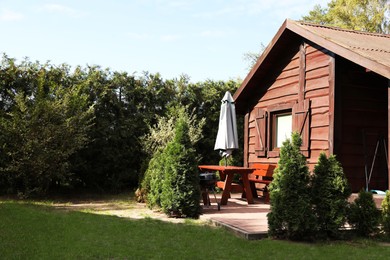 Photo of Cozy wooden house surrounded by lush nature on sunny day