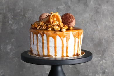 Dessert stand with delicious caramel cake on gray background