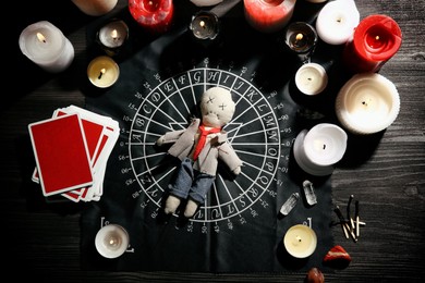 Photo of Voodoo doll pierced with needle surrounded by ceremonial items on table, flat lay