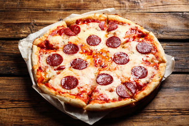 Photo of Hot delicious pepperoni pizza on wooden table