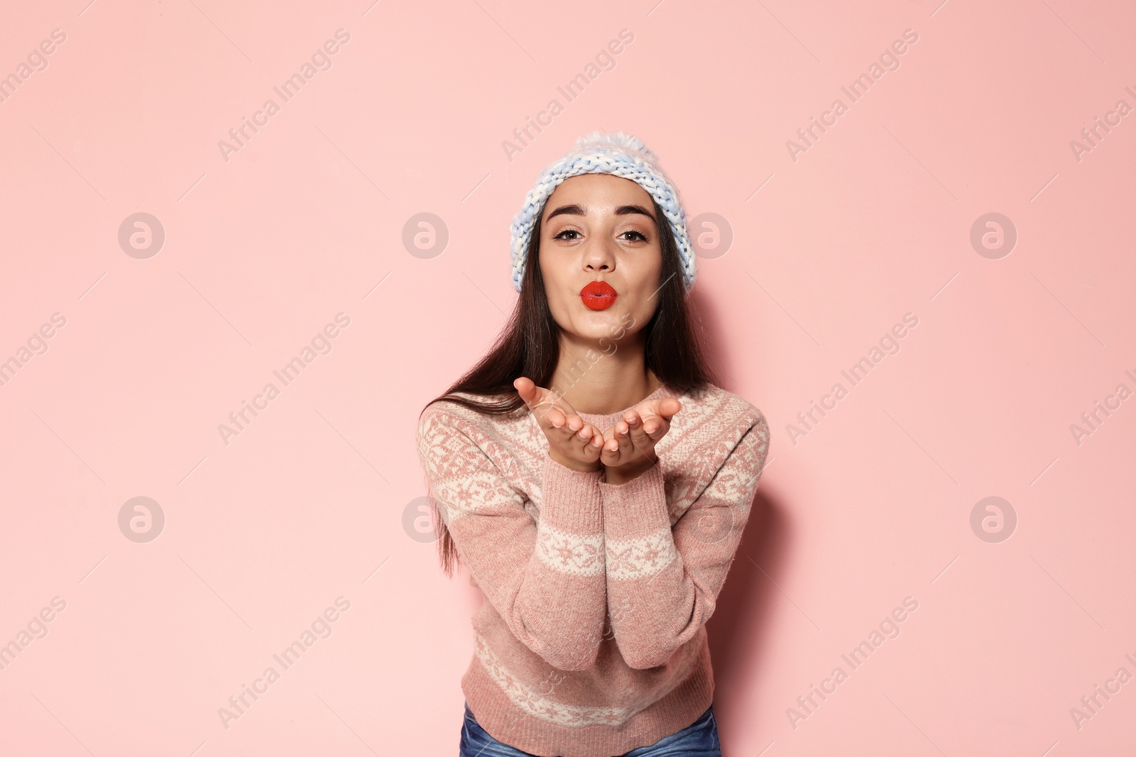 Photo of Young woman in warm sweater and knitted hat on color background. Celebrating Christmas