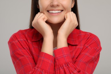 Photo of Young woman with clean teeth smiling on light grey background, closeup
