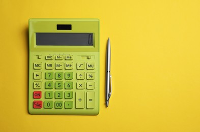 Photo of Calculator and pen on yellow background, flat lay with space for text