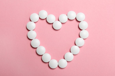 Photo of Heart made with white pills on color background