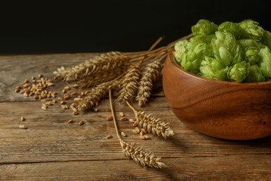 Fresh green hops, wheat grains and spikes on wooden table, space for text