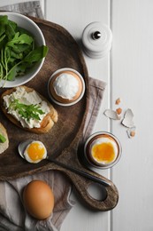 Breakfast with soft boiled eggs served on white wooden table, flat lay