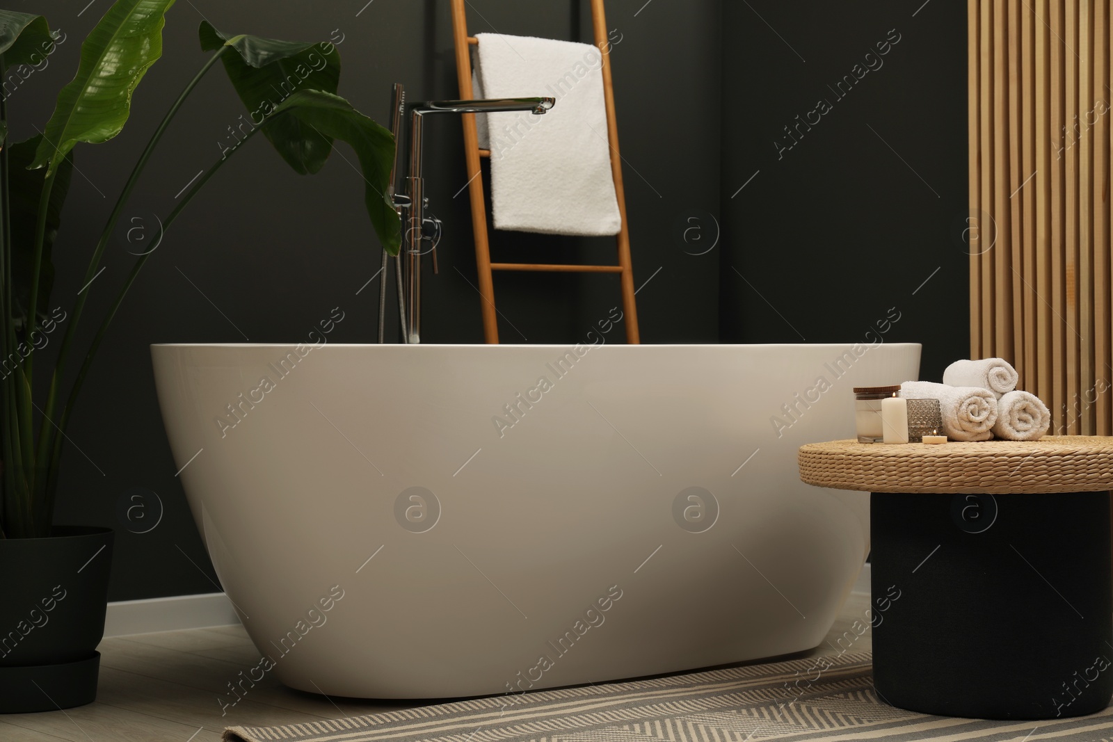 Photo of Spa day. Ceramic tub and wicker table in bathroom