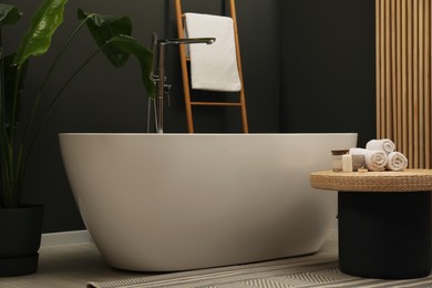 Photo of Spa day. Ceramic tub and wicker table in bathroom