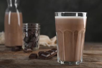 Photo of Glass of chocolate milk on wooden table, closeup. Space for text