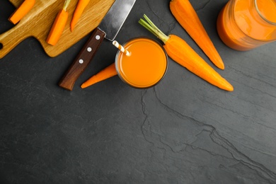 Photo of Freshly made carrot juice on black table, flat lay. Space for text