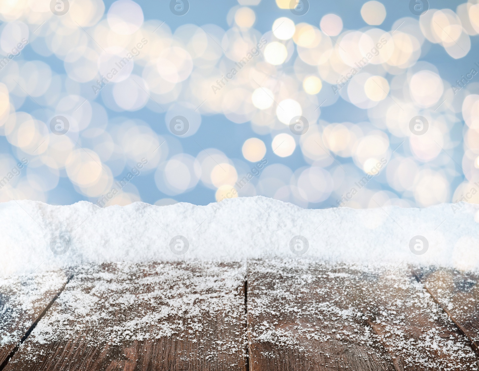 Image of Wooden surface with heap of snow and blurred Christmas lights on background, bokeh effect 