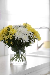 Photo of Vase with beautiful chrysanthemum flowers on countertop in kitchen. Interior design