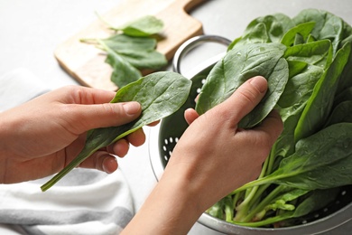 Woman with fresh green healthy spinach on grey table, closeup view