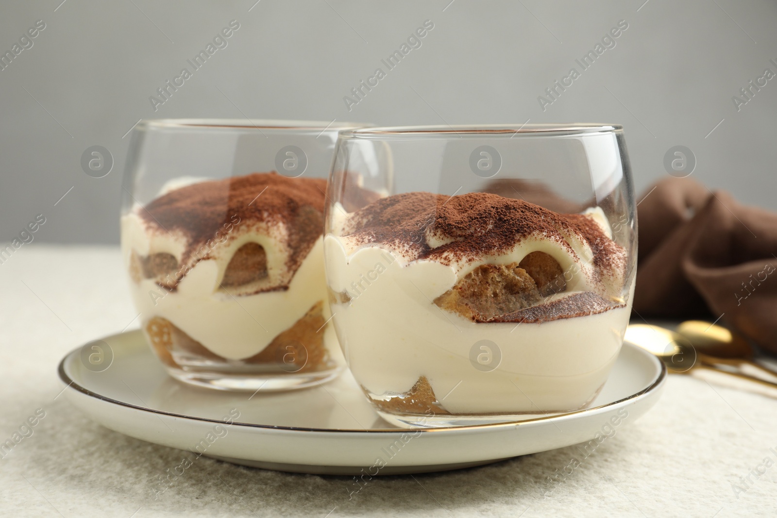 Photo of Delicious tiramisu in glasses on white table, closeup