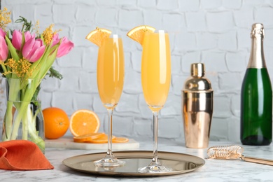 Photo of Glasses of Mimosa cocktail with garnish on white marble table