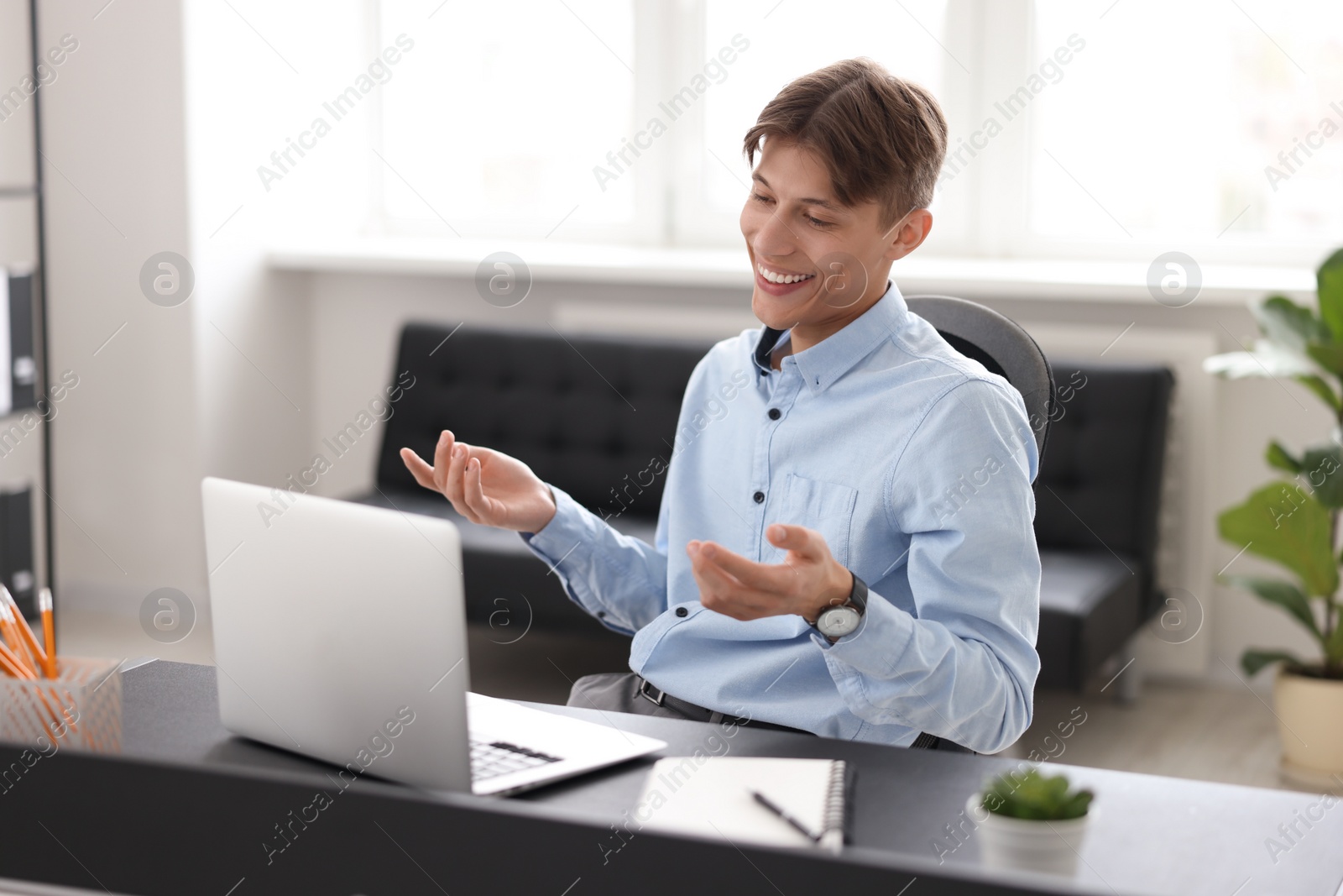 Photo of Man using video chat during webinar at table in office