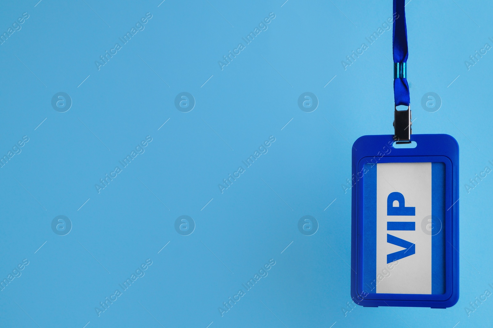 Photo of Plastic vip badge hanging on light blue background, space for text