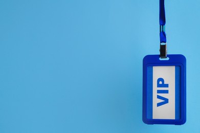 Photo of Plastic vip badge hanging on light blue background, space for text