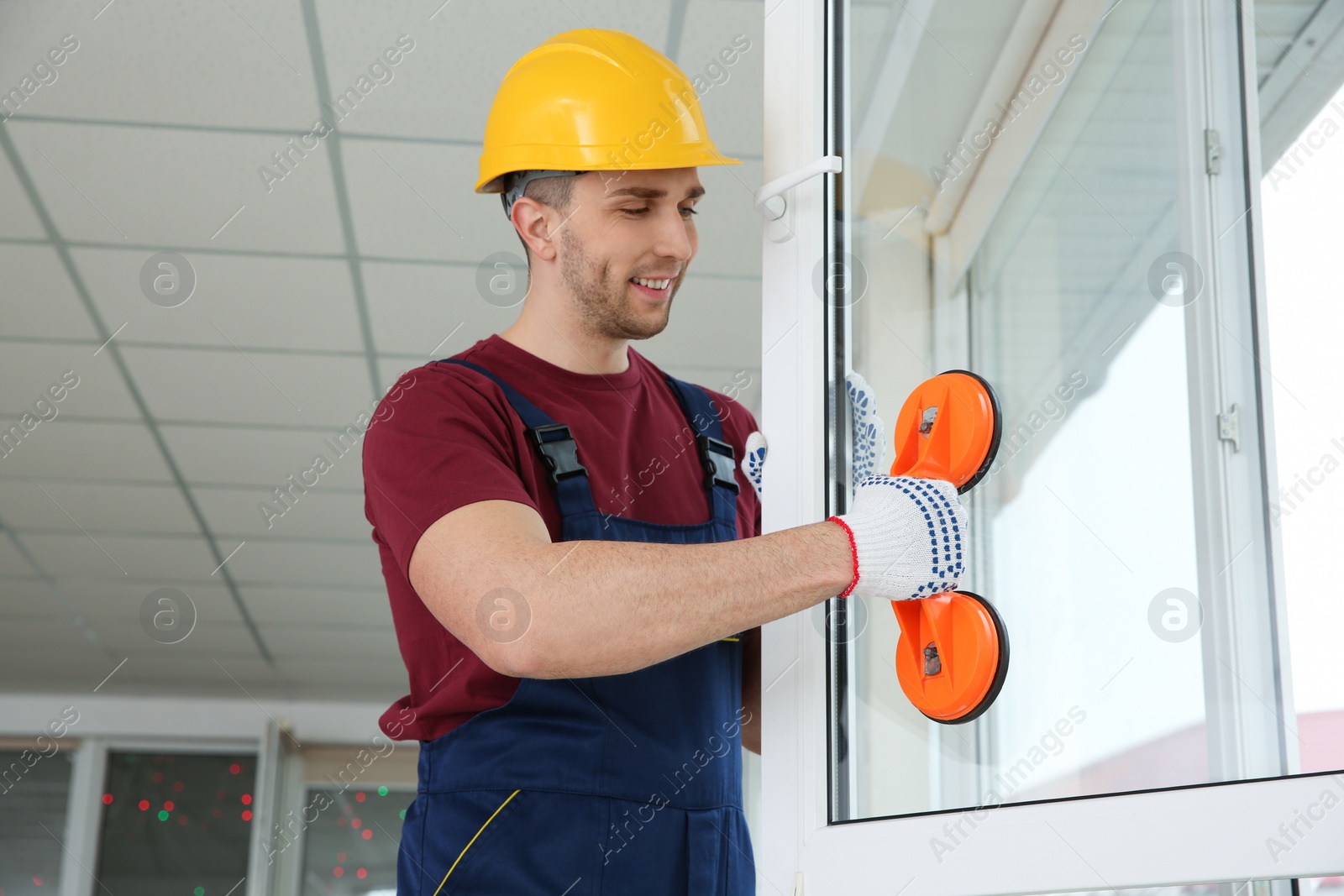 Photo of Construction worker using suction lifter during window installation indoors