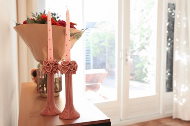 Photo of Bouquet of flowers and candles on wooden table indoors. Space for text