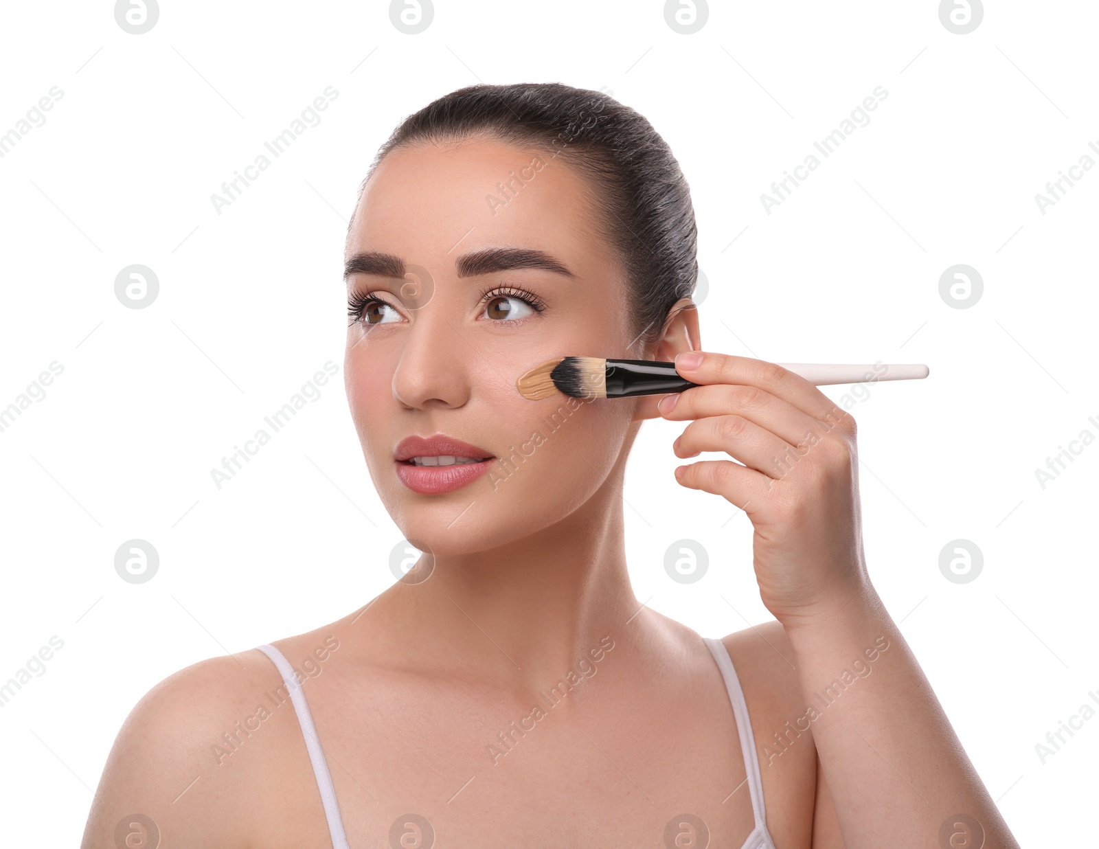 Photo of Woman applying foundation on face with brush against white background