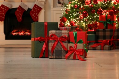 Photo of Many gift boxes near decorated Christmas tree and fireplace indoors