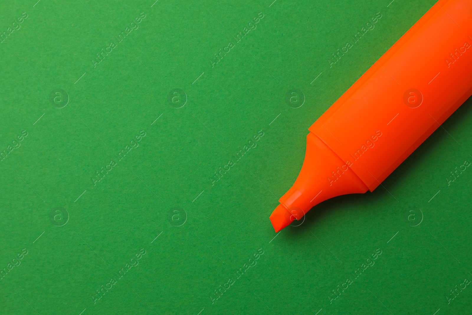 Photo of Bright orange marker on green background, top view. Space for text