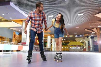 Photo of Young couple spending time at roller skating rink