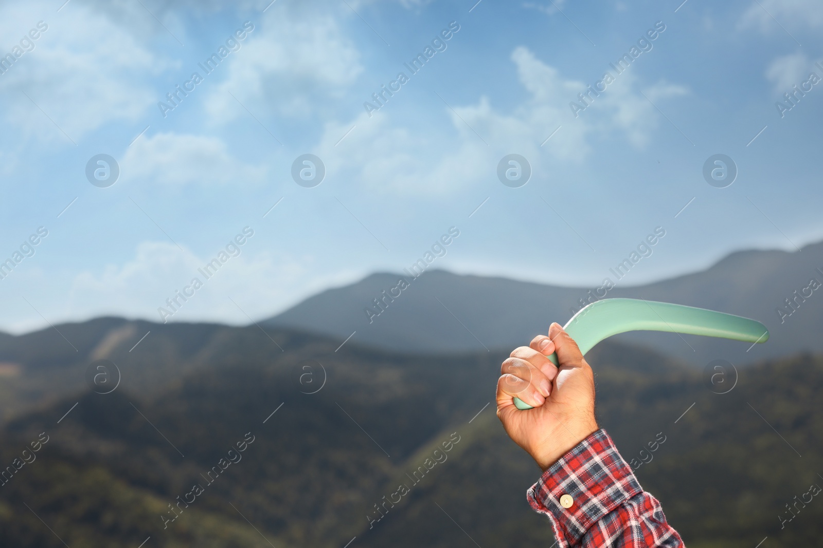 Photo of Man throwing boomerang in mountains, closeup. Space for text