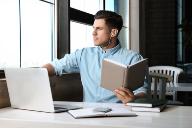 Photo of Man listening to audiobook at table in cafe