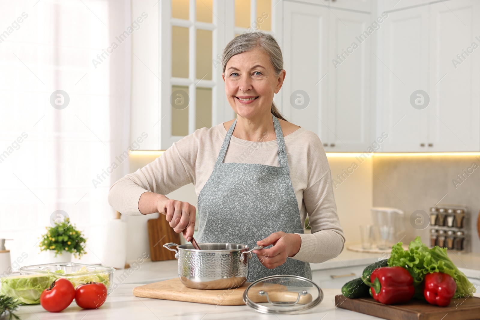 Photo of Happy housewife cooking at table in kitchen