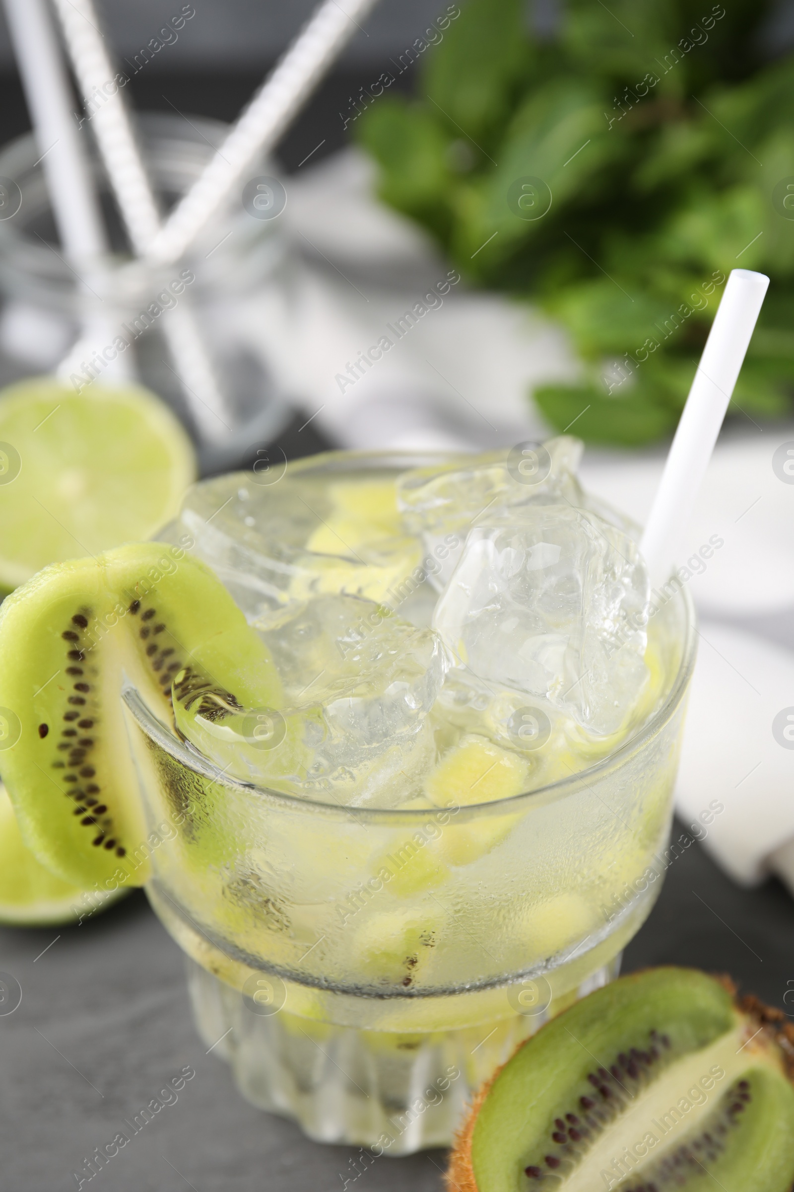 Photo of Glass of refreshing drink and cut kiwi on gray table, closeup