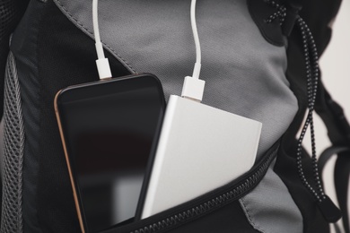 Smartphone charging with power bank in backpack, closeup