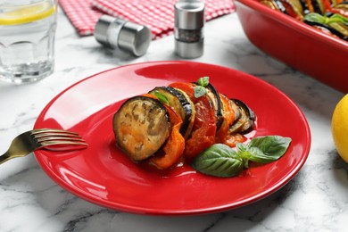 Photo of Delicious ratatouille with basil served on white marble table, closeup