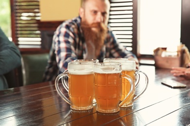 Photo of Glasses of tasty beer on table indoors