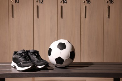 Photo of Soccer ball and sneakers on wooden bench in locker room