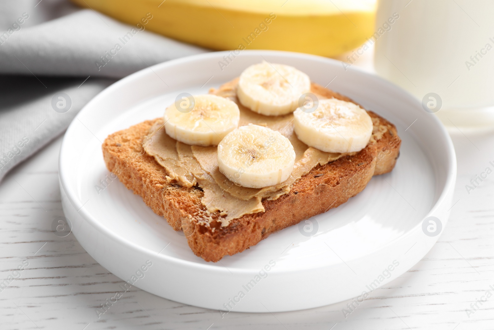 Photo of Toast with peanut butter and banana on white wooden table, closeup. Healthy breakfast