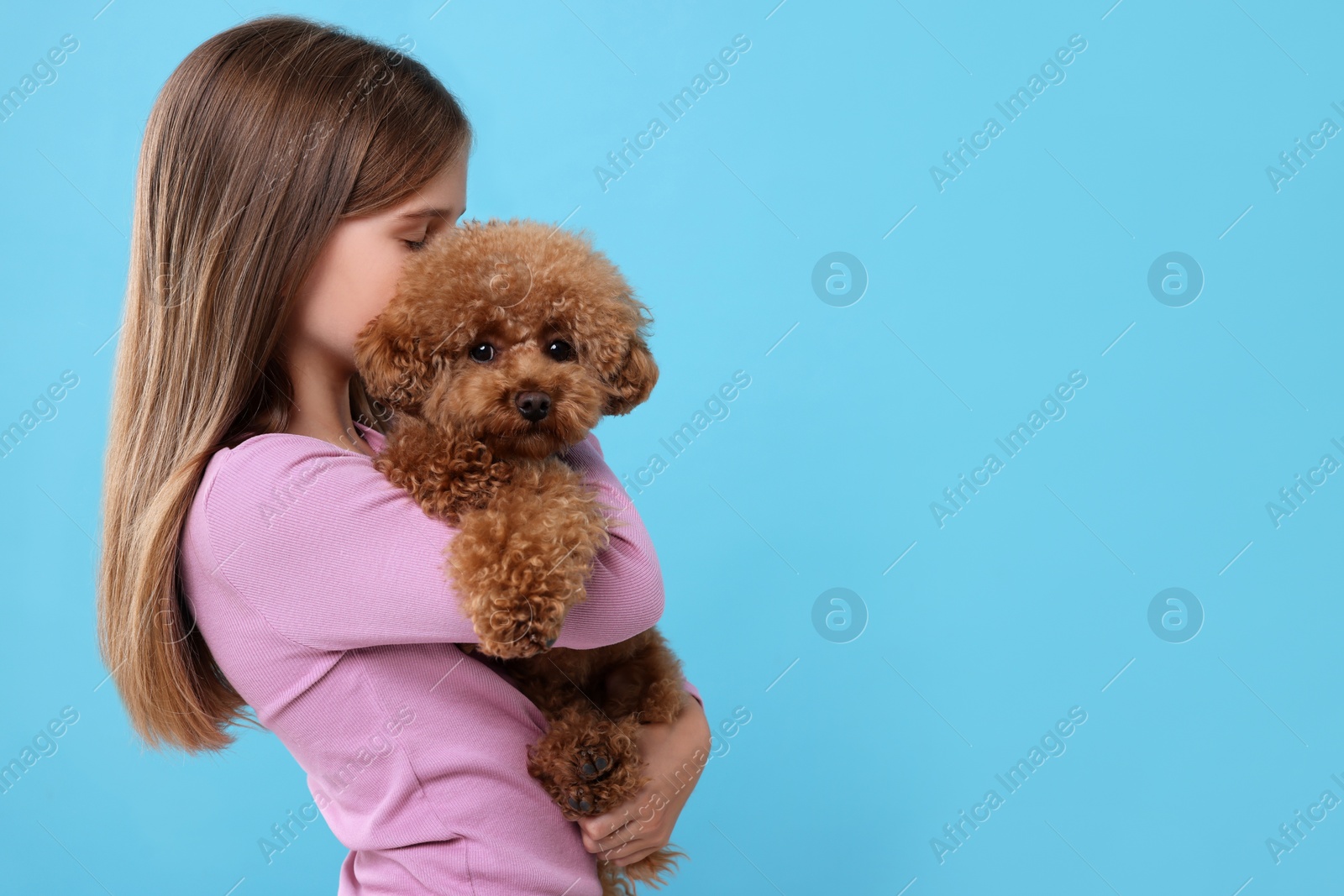 Photo of Little child with cute puppy on light blue background, space for text. Lovely pet