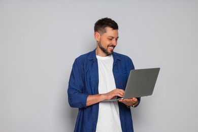 Photo of Smiling man with laptop on light grey background