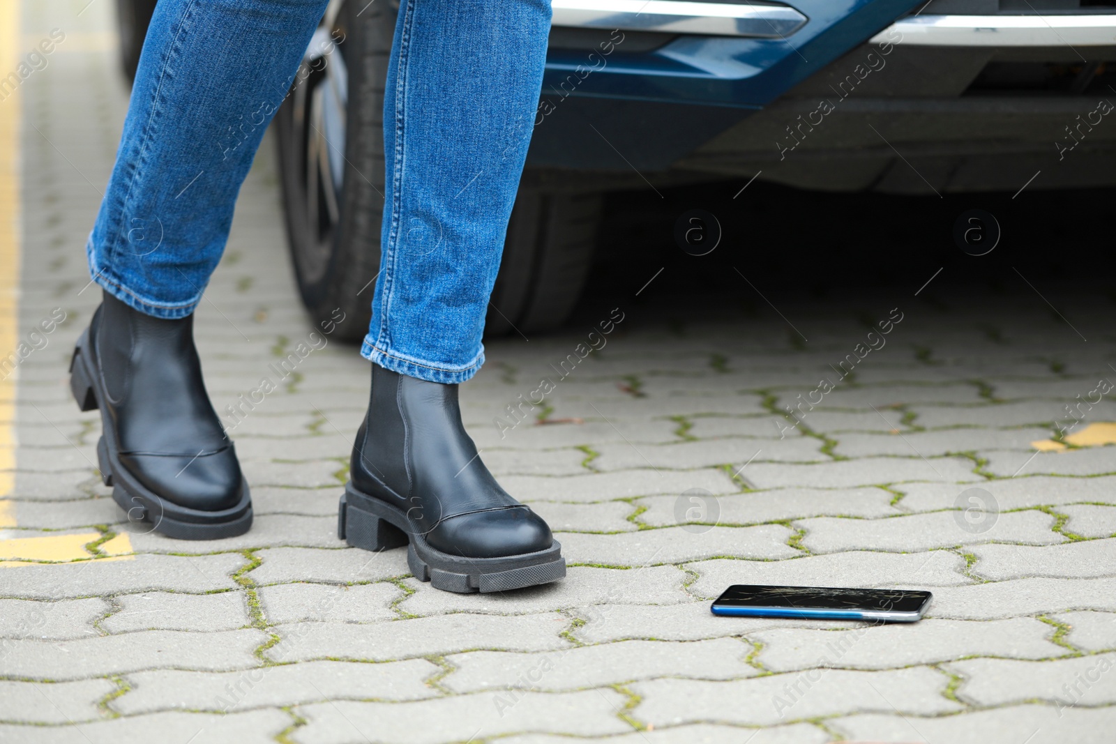 Photo of Woman near dropped smartphone on pavement, closeup. Device repairing