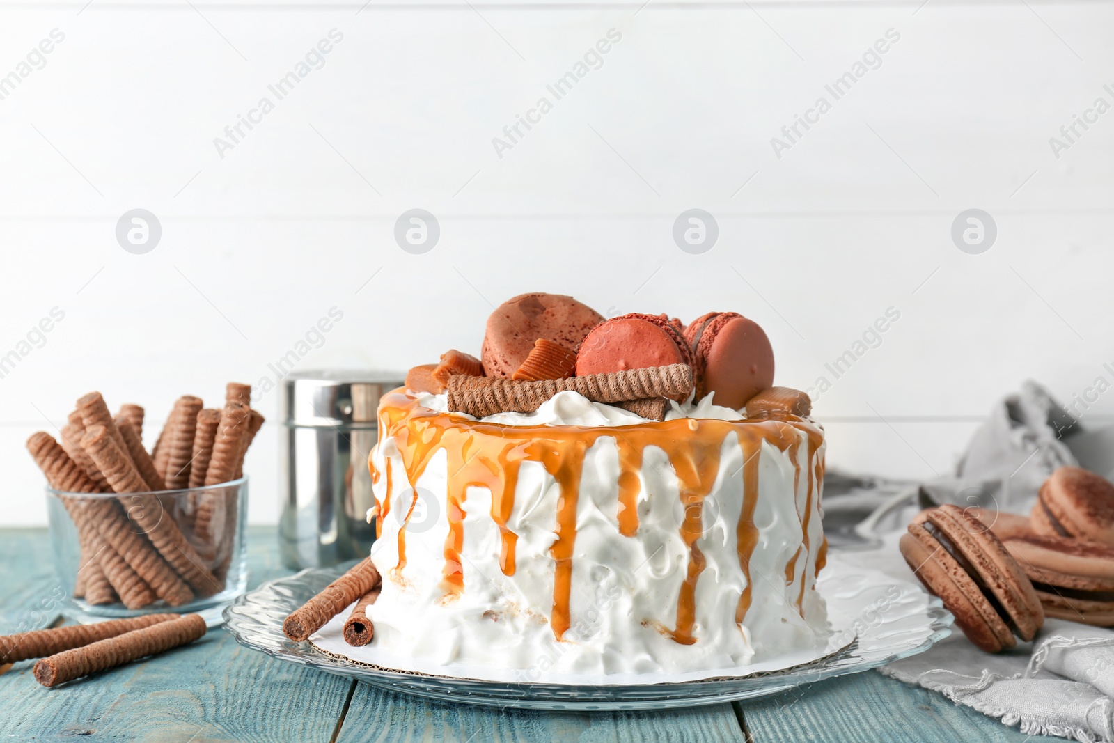 Photo of Delicious homemade cake with caramel sauce and cookies on table