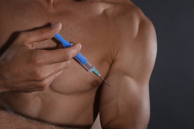 Photo of Athletic man injecting himself on grey background, closeup. Doping concept