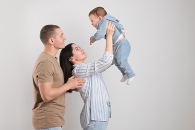 Happy parents with cute child on light background