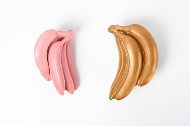 Stylish gold and pink bananas on white background, top view