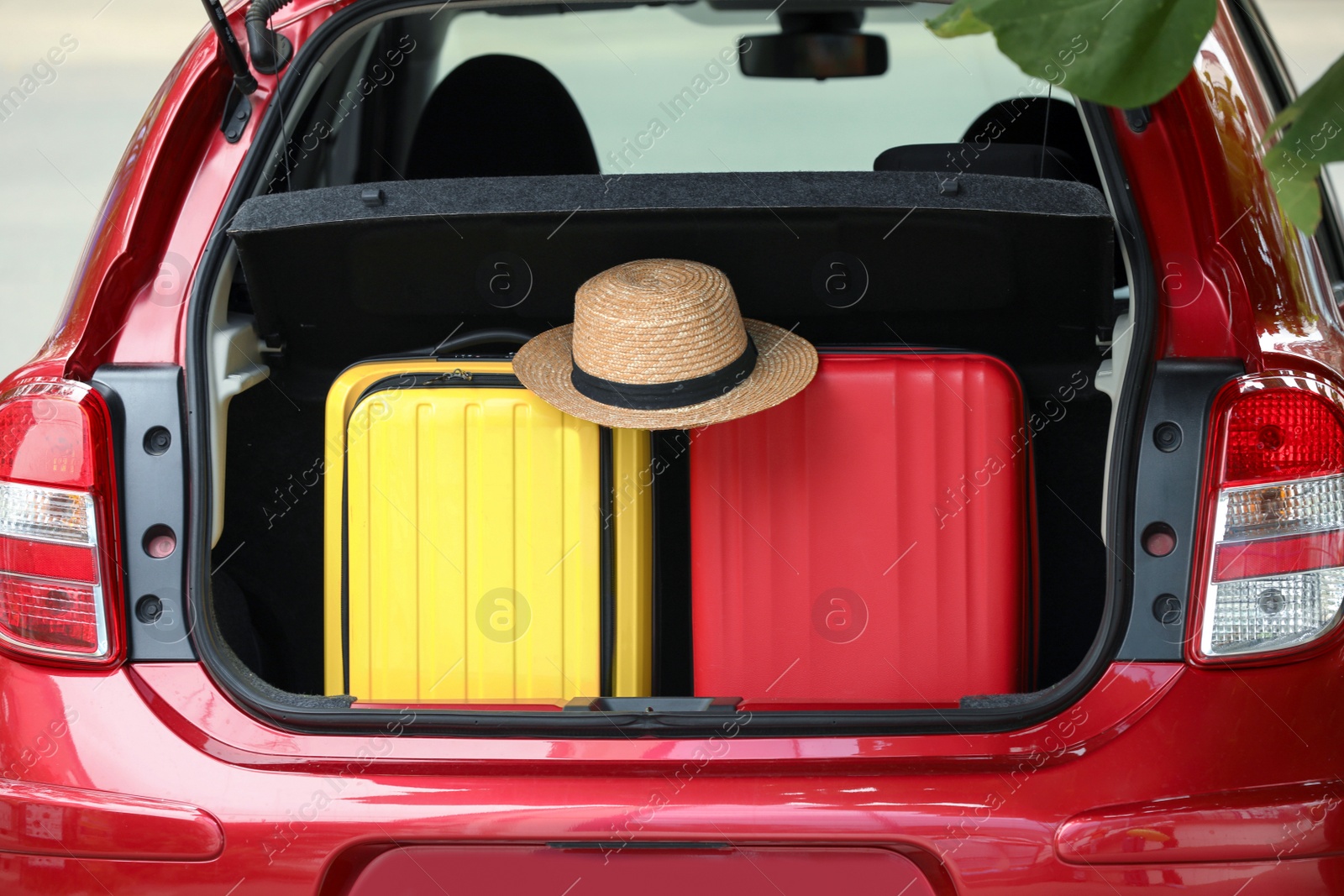 Photo of Suitcases and hat in car trunk outdoors, closeup