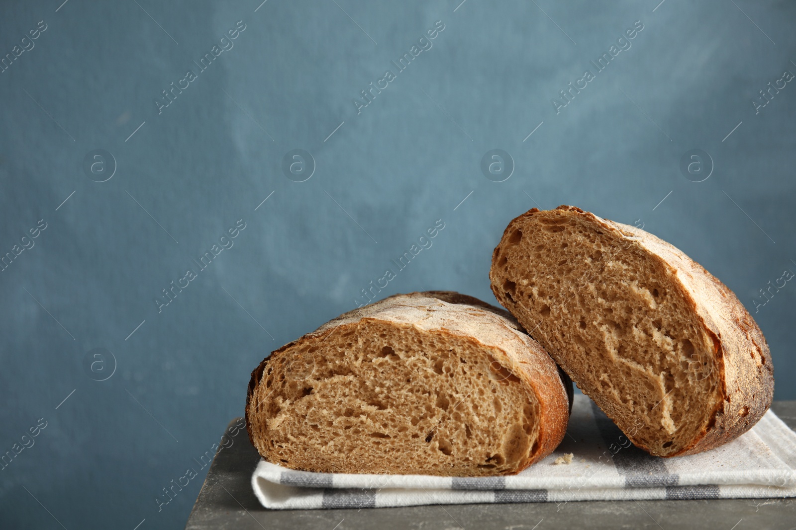 Photo of Cut loaf of bread on table against color background. Space for text