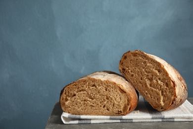 Cut loaf of bread on table against color background. Space for text