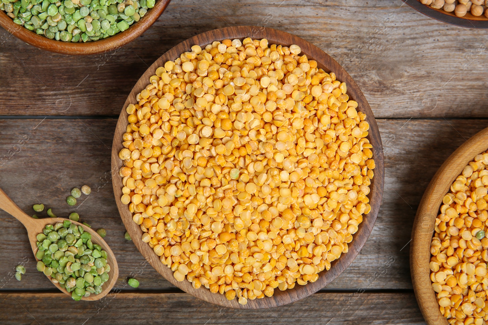 Photo of Bowls and spoon with dried peas on wooden background, top view